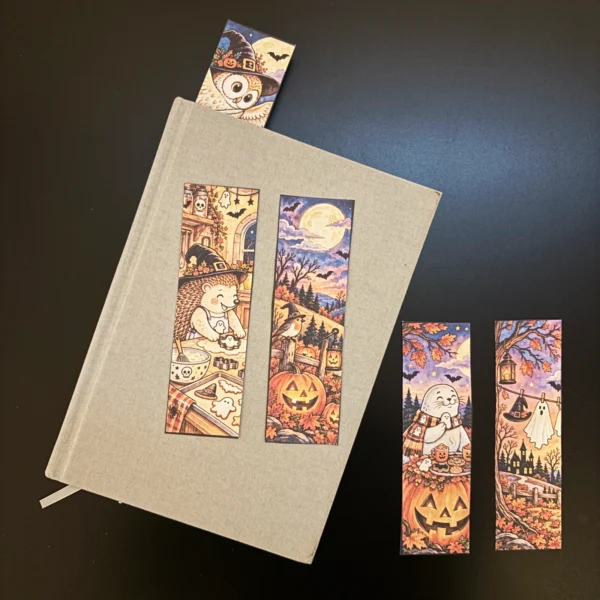 Bokmärken - Nordisk (åh så söt!) Halloween 1 Utskrivna Halloweenbokmärken från Nordisk Lagom med uggla, igelkott, säl, pumpor och höstmotiv, placerade på och bredvid en bok.